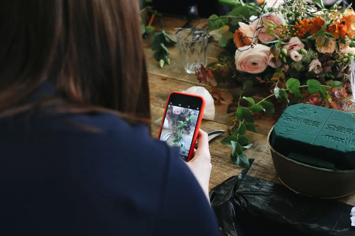 En florist fotograferar sin bukett med mobilen